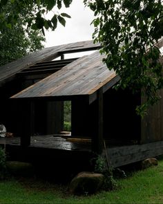 a small wooden structure sitting on top of a lush green field next to a forest