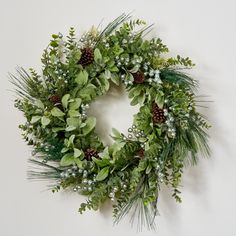 a green wreath with pine cones and greenery