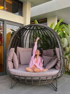 a woman sitting in a hanging chair on the ground