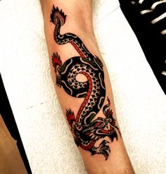 a black and red dragon tattoo on the arm