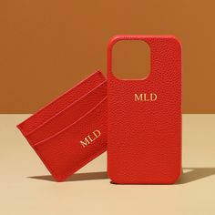 a red leather case with the name mild on it and a matching card holder are sitting next to each other