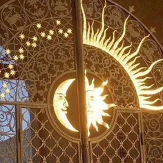 the sun and moon are lit up in front of an iron gate