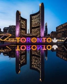 the words toronto are lit up at night in front of some skyscrapers and water