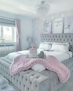 a bed with a pink blanket on top of it next to a chandelier