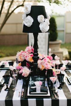 a black and white striped table cloth with pink flowers on it, along with an elegant lamp shade