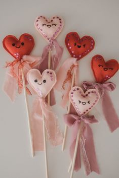 four heart - shaped lollipops with bows and sequins on them