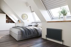 a bed sitting under a window next to a radiator in a room with wooden floors