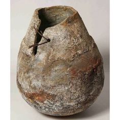 an old stone vase with rusted paint on the outside and inside, sitting on a white surface