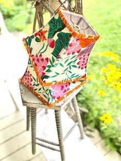 an umbrella sitting on top of a wooden chair next to yellow and green flowers in the background