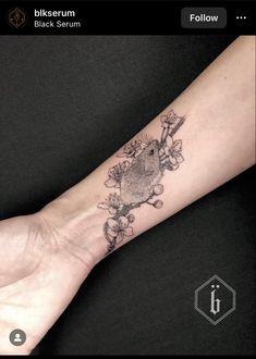 a small tattoo on the arm of a person with a bird and flowers around it