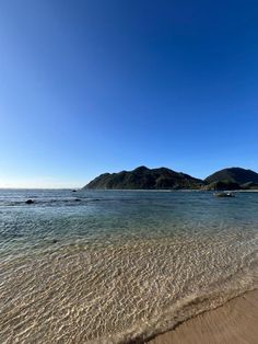 the water is crystal clear and there are mountains in the distance on the other side