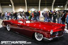 an old red car is on display at a car show