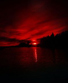 the sun is setting over water with trees in the background