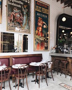 a restaurant with tables and chairs in front of two posters on the wall above them