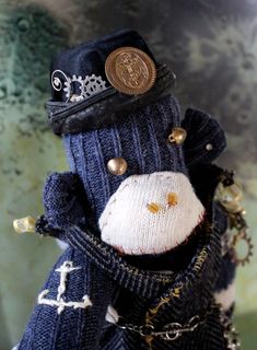 a stuffed animal wearing a blue sweater and hat with chains around it's neck