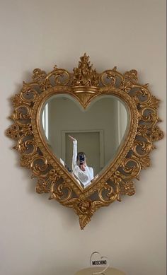 a person taking a selfie in front of a heart shaped mirror on the wall