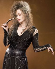 a woman dressed in black holding a pipe and wearing an elaborate dress with long sleeves