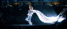 a woman is dancing in the rain with her long white dress flowing over her head