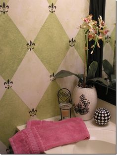 a white sink sitting under a bathroom mirror next to a vase with flowers in it