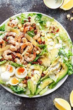 a salad with shrimp, lettuce and eggs on top is shown in a white plate