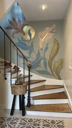 a stair case with painted flowers on the wall and wooden steps leading up to it