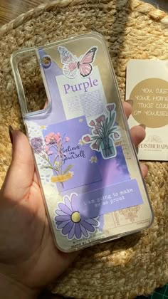 a person holding up a phone case with purple flowers on it and a tag attached to the back