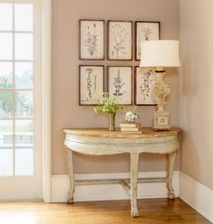 a white table sitting in front of a window with pictures on the wall above it