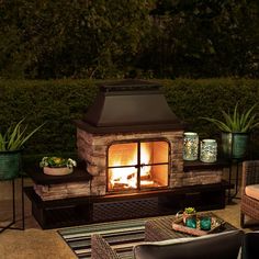 an outdoor fireplace lit up at night with potted plants