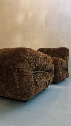 two brown chairs sitting next to each other on a blue floor