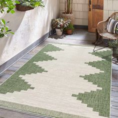 a green and white rug sitting on top of a wooden floor next to potted plants