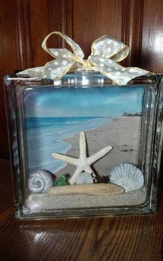 a glass box with seashells and starfish on the beach