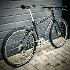 a black and silver bike parked in front of a garage door next to a brick sidewalk