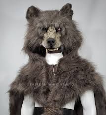 a stuffed bear is wearing a fur coat and leather pants with an attached collar on it's chest