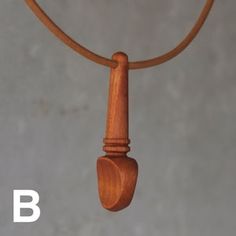 a wooden object is hanging from a leather cord on a gray background with the word b below it