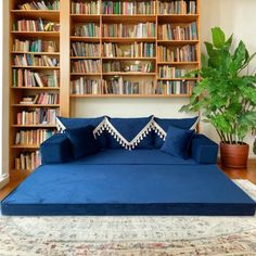 a large blue bed sitting in front of a book shelf filled with books