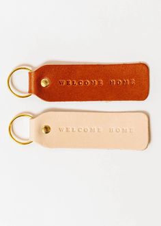 two leather keychains with the words welcome home on them