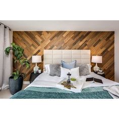 a bedroom with wood paneling on the wall and white bedding, along with two lamps