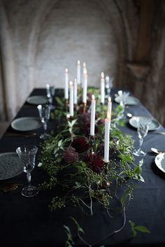 a long table with candles and flowers on it is set up for a formal dinner