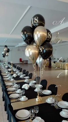 a long table with black and white plates, silver and gold balloon centerpieces