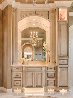 a fancy bathroom with chandelier and marble flooring, along with an arched doorway that leads to another room