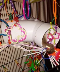 a bird cage filled with lots of different colored toys and decorations hanging from it's sides