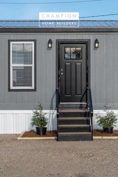 the front entrance to champion home builder's with black door and steps leading up to it