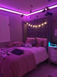 a bedroom with purple lighting and pink bedding