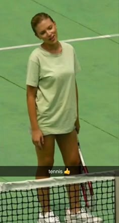 a woman standing on top of a tennis court holding a racquet next to a net