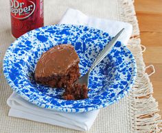 a piece of chocolate cake on a blue and white plate next to a cup of coffee