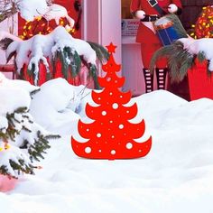 a red christmas tree in front of a house with santa clause on it's back