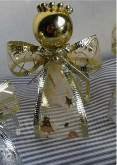 a gold christmas ornament sitting on top of a striped pillow with ribbon around it