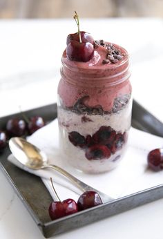 a dessert in a jar with cherries on the side