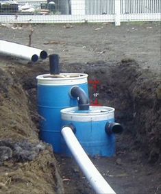 two blue and white water tanks sitting next to each other in the middle of a dirt field