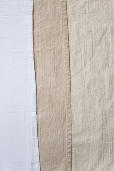 three different colors of linens laid out on top of each other, one white and the other beige